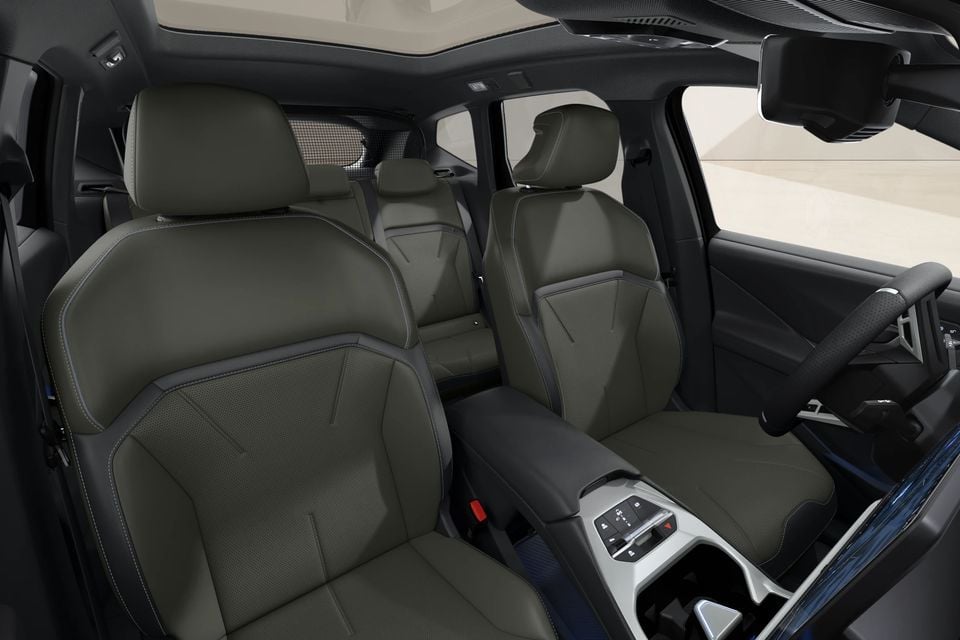 Interior of a BMW iX3 showing olive green leather front seats and centre console with a steering wheel visible on the right