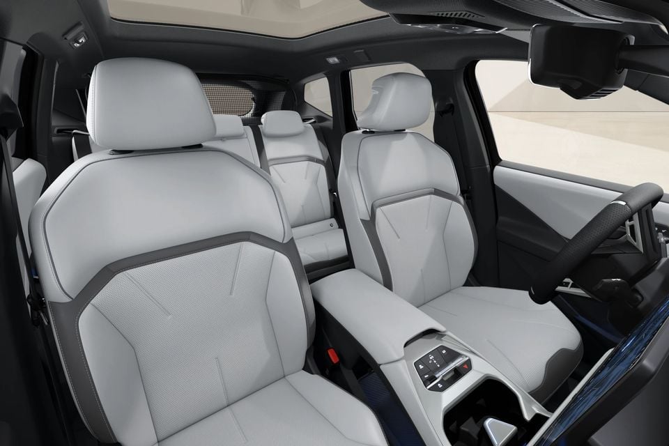 Interior of a BMW iX3 showing light grey leather front and rear seats with a centre console and steering wheel visible
