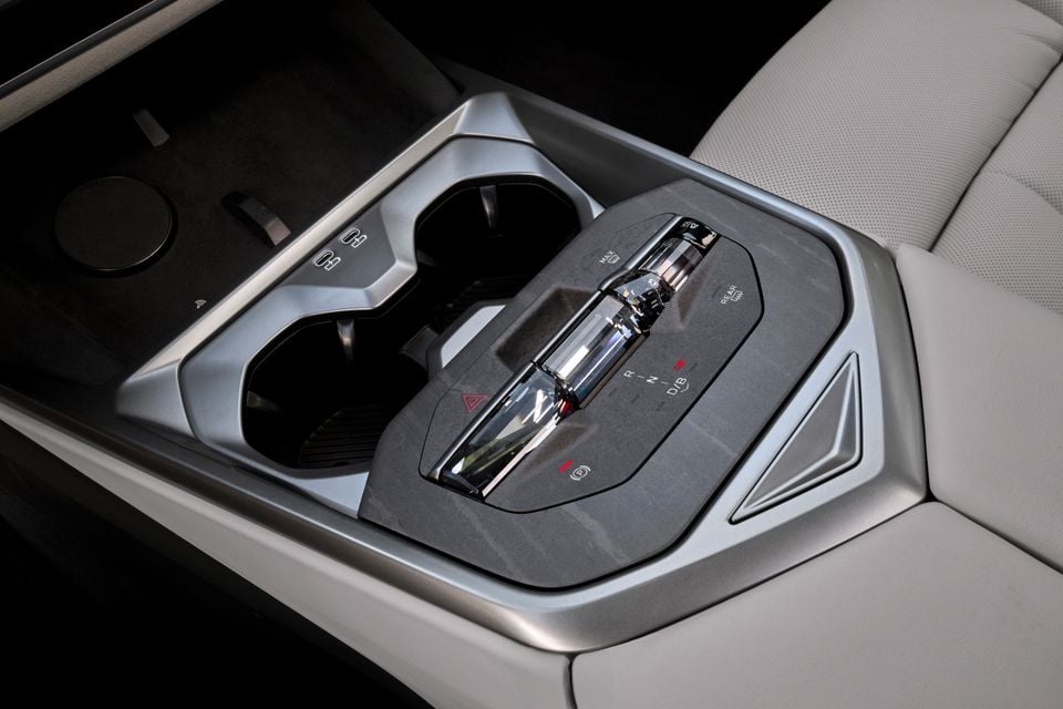 Close-up of the BMW X5 centre console showing a crystal-style gear selector with R, N, D and B markings, surrounded by cup holders and control buttons