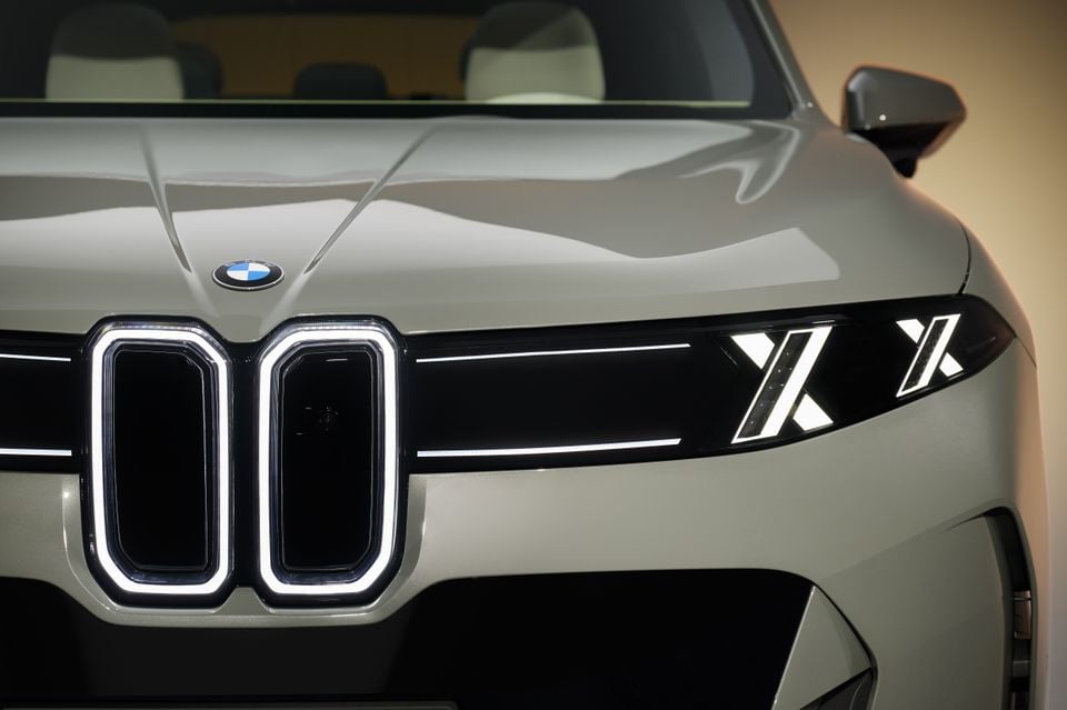 Close-up of the front grille and headlights of a BMW X5 SUV in a light grey colour, showing the illuminated kidney grille and X-shaped daytime running lights