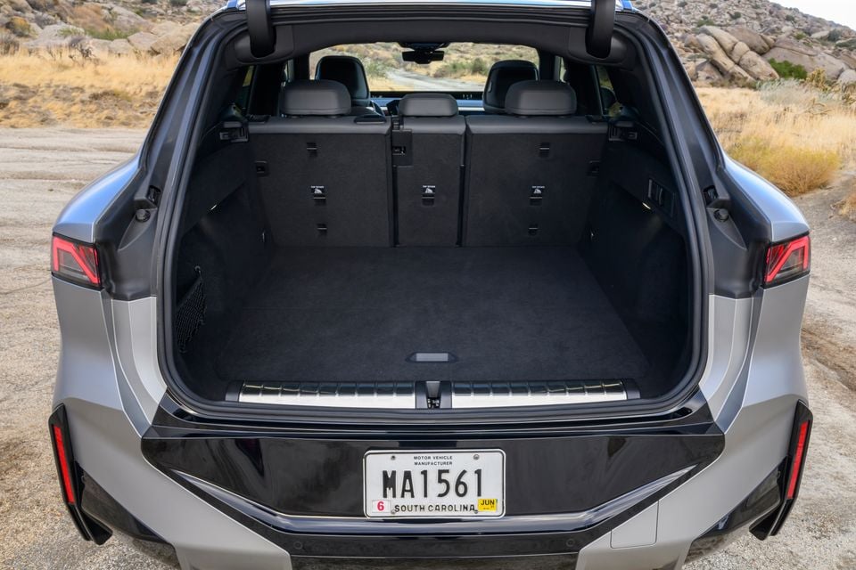 The open boot of a silver BMW X5 xDrive40 SUV seen from the rear, showing the carpeted cargo area with rear seats upright