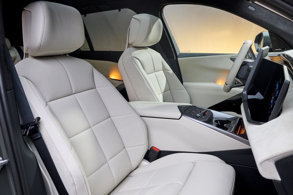 Light cream leather interior of a BMW X5 showing front and rear seats, centre console, and infotainment screen