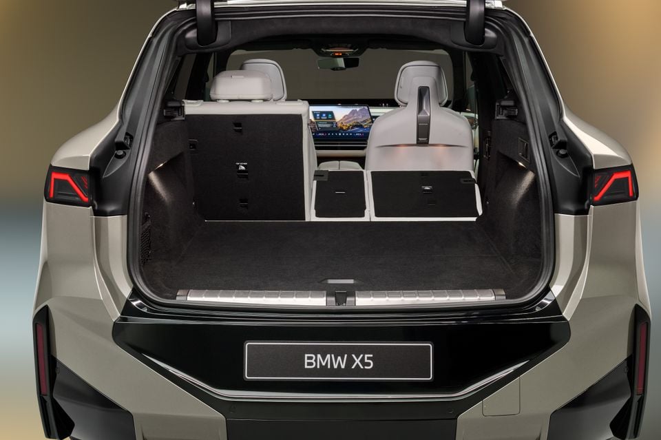 Boot space of a BMW X5 SUV viewed from the rear, showing a large open cargo area with folding third-row seats and a central infotainment screen visible through the cabin