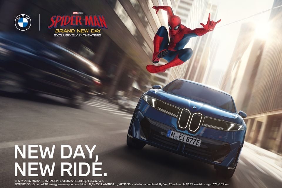 A BMW iX3 SUV driving through a city street in a promotional advertisement featuring Marvel's Spider-Man, with the text 'New Day, New Ride' and the Spider-Man: Brand New Day movie logo.
