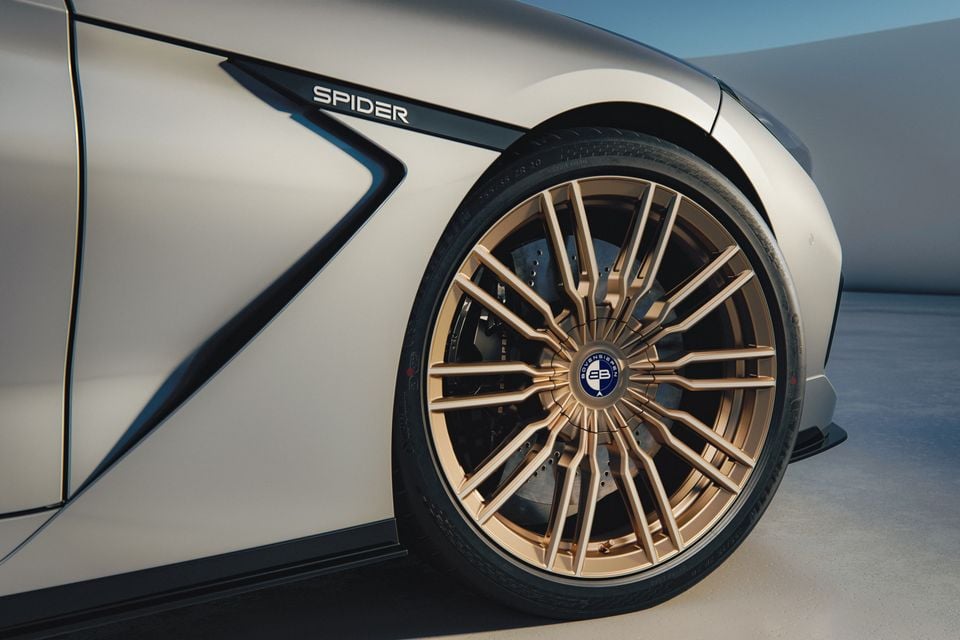 Close-up of a gold multi-spoke alloy wheel and large brake disc on a Bovensiepen Spider sports car, with the 'Spider' badge visible on the body panel