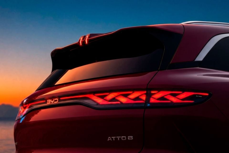 Close-up of the illuminated LED tail-lights and Atto 8 badge on a red BYD Atto 8 SUV at sunset