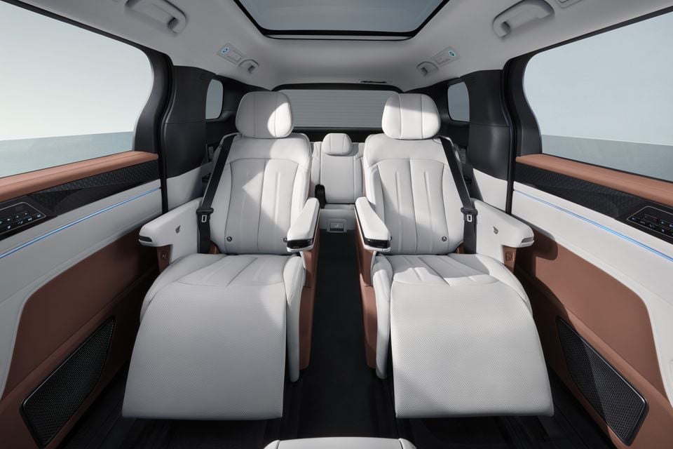 Luxurious white leather captain's chairs in the rear cabin of a BYD M9, with brown leather door trims, blue ambient lighting, and a panoramic sunroof overhead