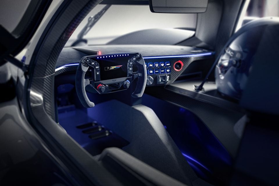 Interior of the Cadillac V concept car showing a racing-style flat-bottom steering wheel with a digital display, carbon fibre dashboard, and blue ambient lighting
