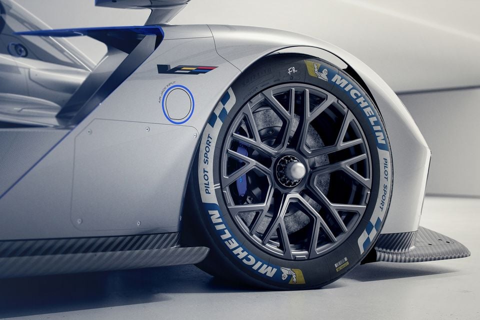 Close-up of the front wheel and tyre on the Cadillac V-LMDh concept race car, showing a Michelin Pilot Sport racing tyre, multi-spoke alloy wheel, blue brake caliper, and carbon fibre bodywork details