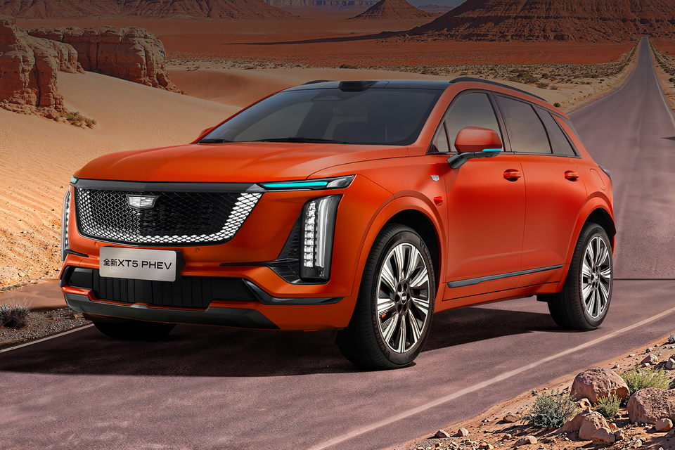 An orange Cadillac XT5 PHEV SUV seen from the front-side angle against a desert backdrop