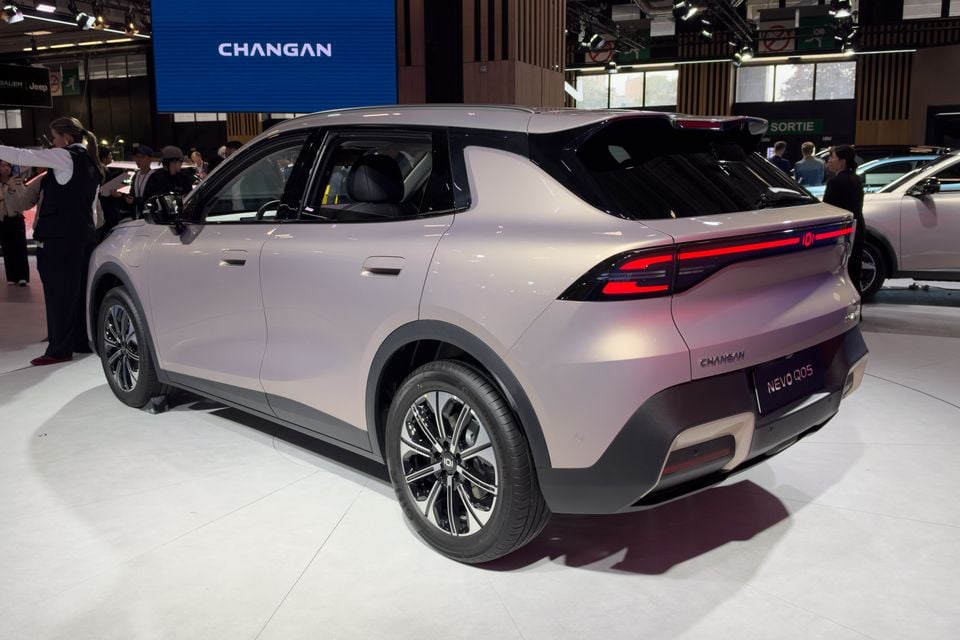 A champagne-coloured Changan Nevo Q05 SUV on display at a motor show, seen from the rear quarter with its full-width light bar illuminated