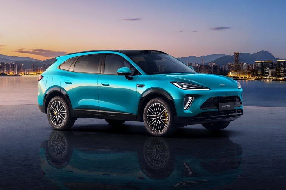 A teal Chery Fulwin T9L SUV shown from the front-side angle, set against a city skyline at dusk