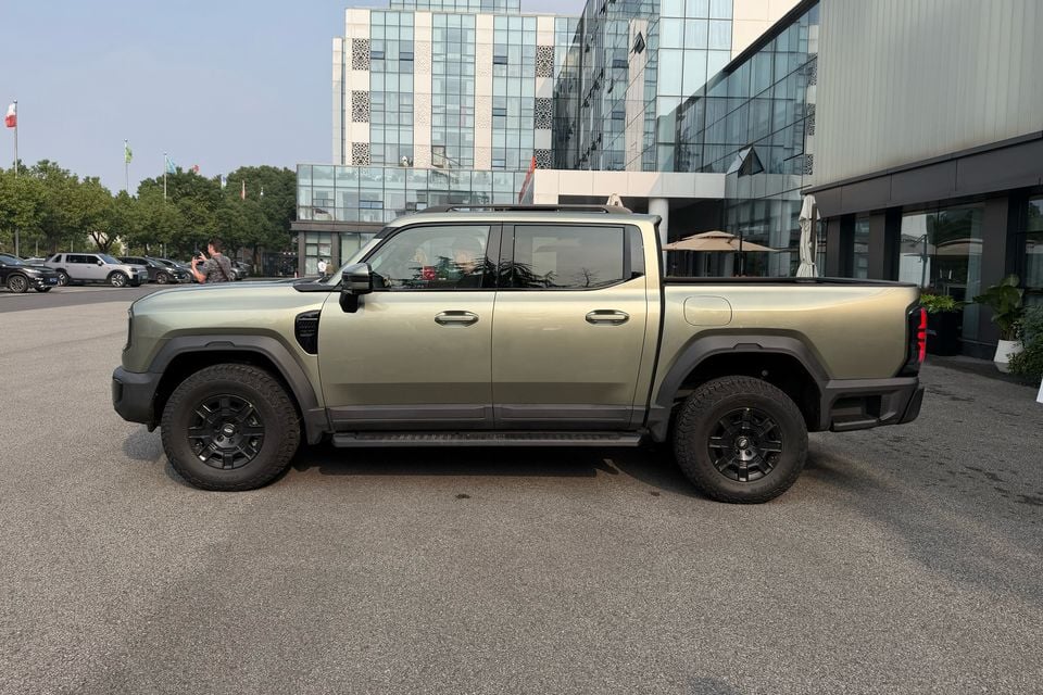 Khaki Chery Stockman dual-cab ute in side profile outside an event venue.