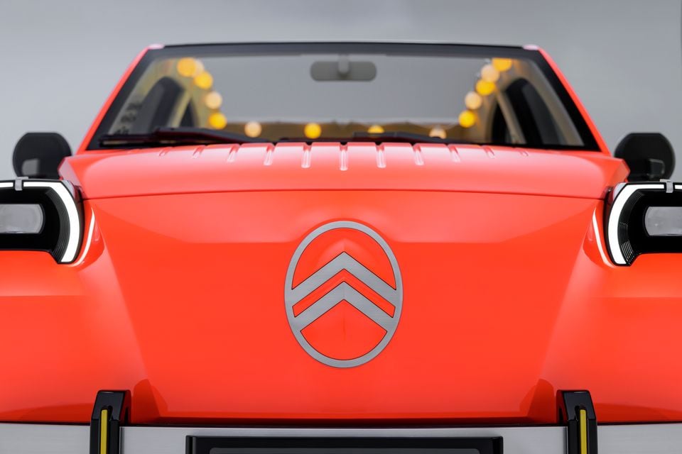 Front of an orange Citroen concept car seen head-on, showing the oval chevron badge, slim LED headlights and upright windscreen