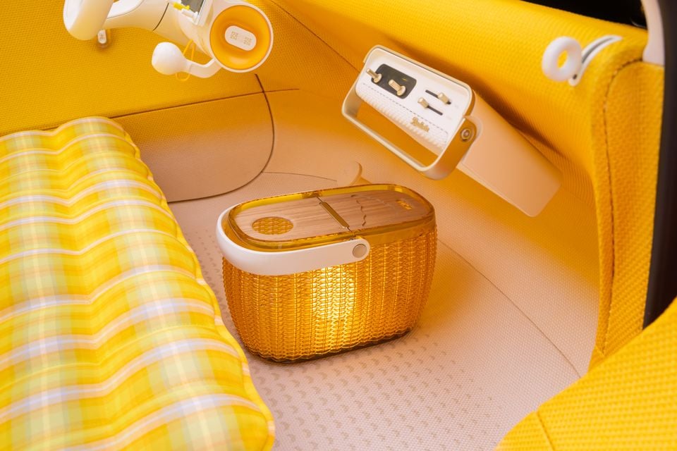 Yellow cabin of the Citroen 2CV concept with a woven basket on the floor, a checked inflatable seat and a retro-style control panel on the dashboard