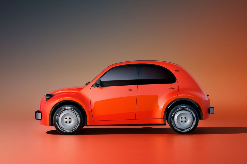 An orange Citroen 2CV concept small hatchback shown in side profile against an orange studio backdrop