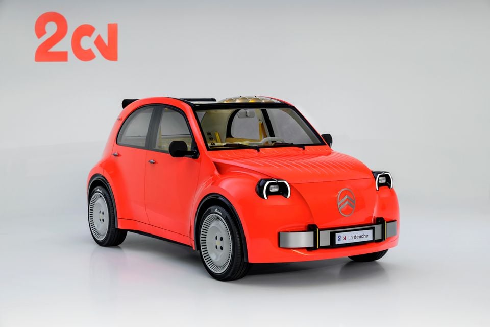 A red Citroen 2CV concept hatchback seen from the front three-quarter angle in a white studio, with a La deuche number plate