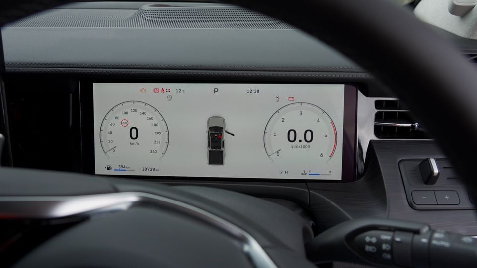 Digital instrument cluster display showing speedometer and tachometer with a top-down vehicle graphic, reading 0 km/h and parked