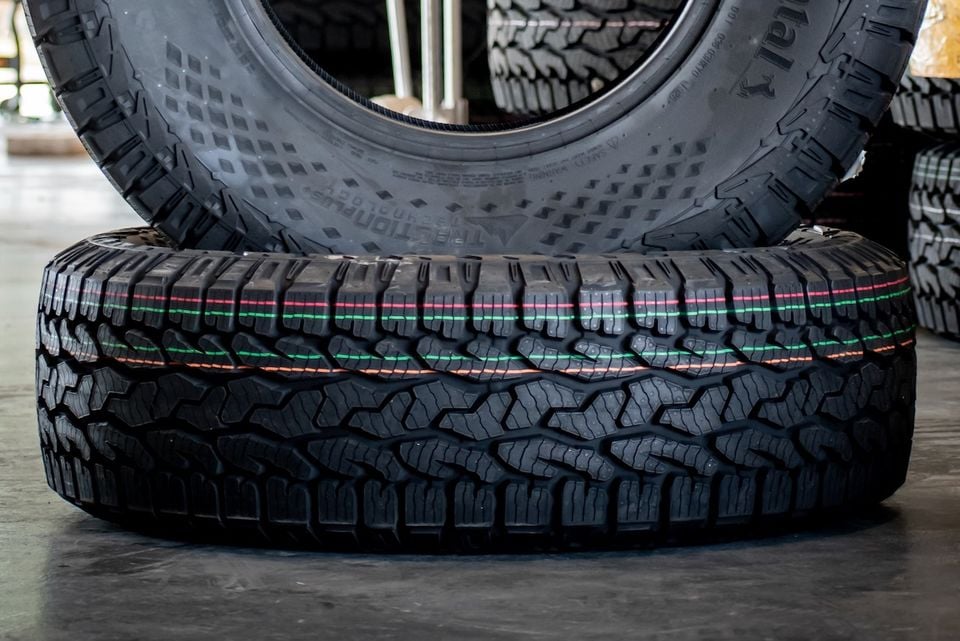Close-up of Continental CrossContact AT2 all-terrain tyres stacked on a floor, showing aggressive tread pattern with coloured marker stripes