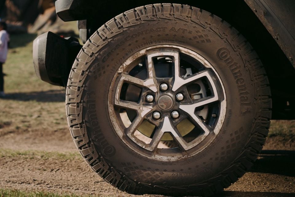 Close-up of a mud-covered Continental CrossContact A/T2 all-terrain tyre and alloy wheel on a vehicle after off-road driving