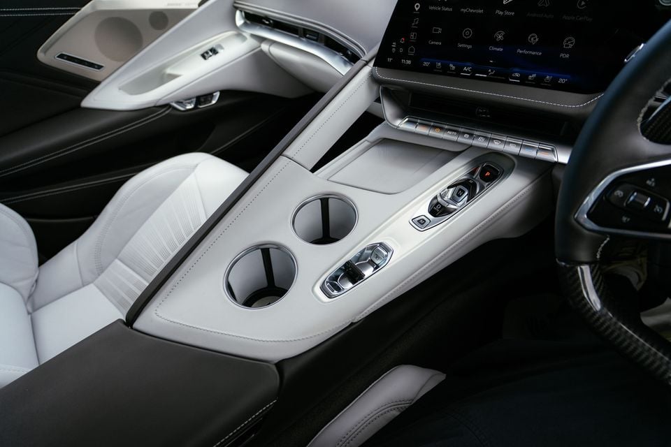 Close-up of the white leather centre console with cup holders, gear selector buttons and infotainment screen in a Chevrolet Corvette Z06.