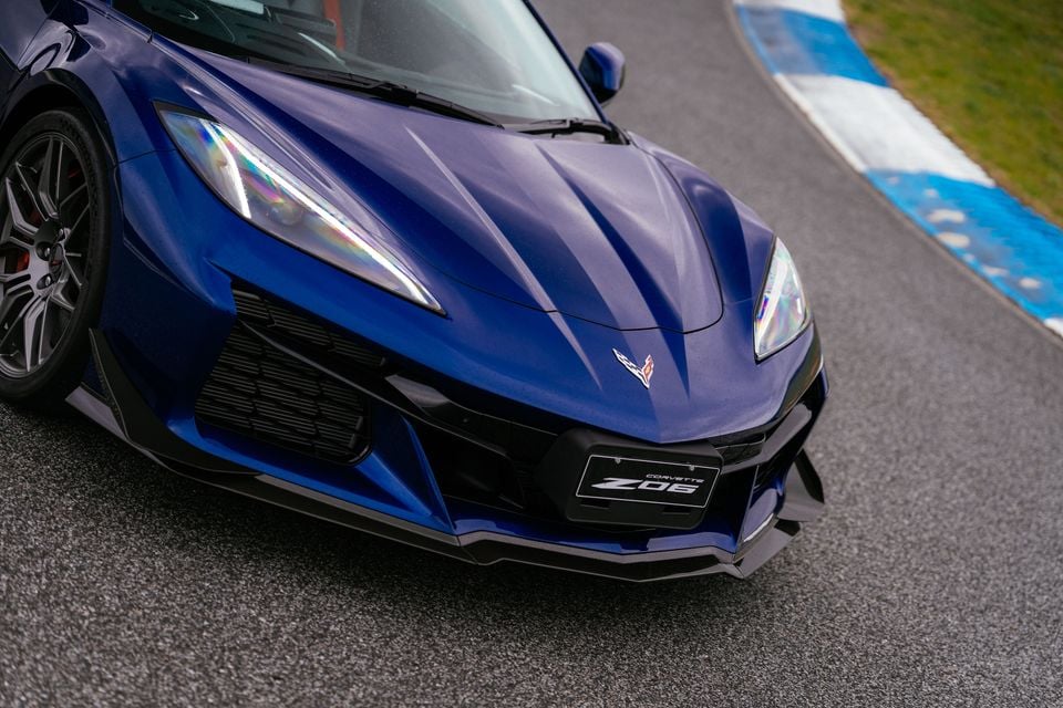 A blue Chevrolet Corvette Z06 sports car is shown close up from the front quarter angle on a race track.