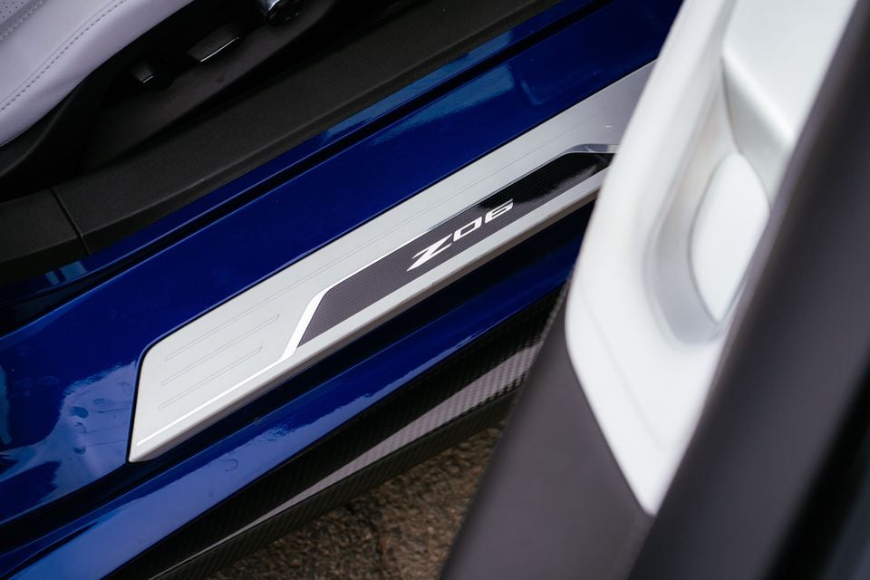 Close-up of the Chevrolet Corvette Z06 door sill badge on a blue car's carbon-fibre side skirt