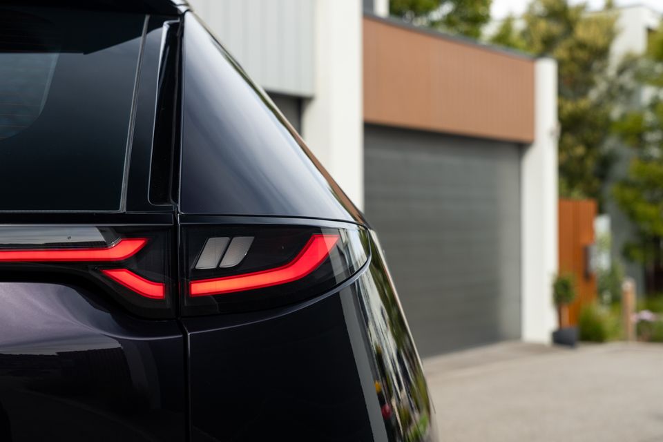 Close-up of the dark taillight on a black car, likely a Nissan Qashqai or similar crossover, parked in a driveway