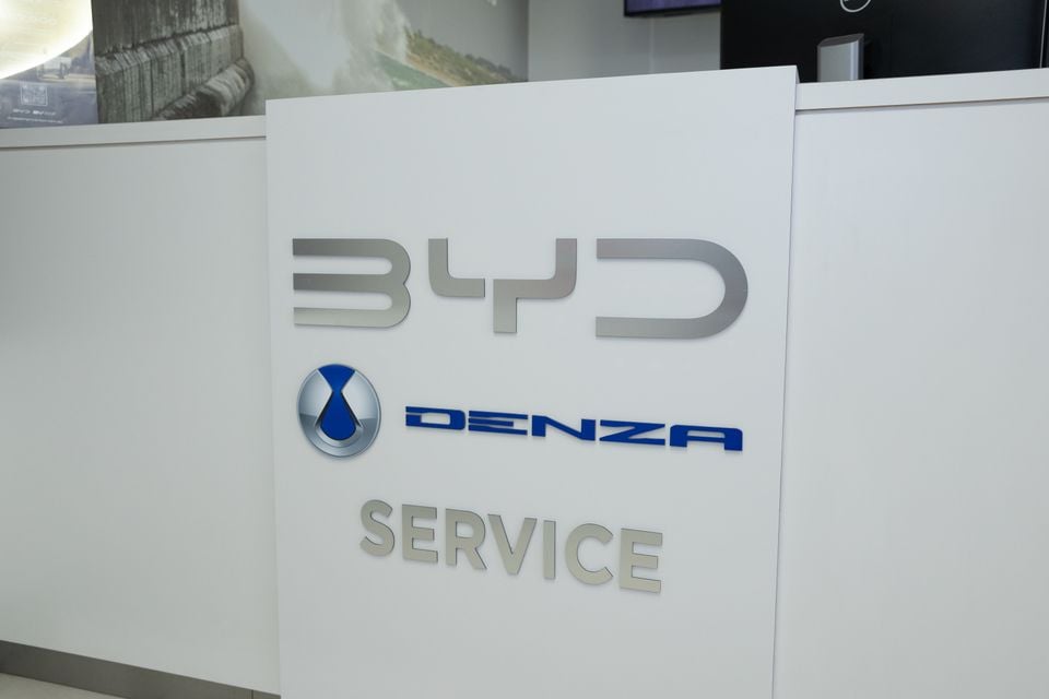 BYD and Denza logos above the word Service on a white reception counter at a dealership service centre
