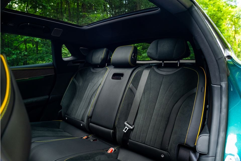 Rear passenger seats of a Denza Z9 GT featuring black upholstery with yellow contrast stitching, a panoramic sunroof, and seatbelts visible inside the cabin.