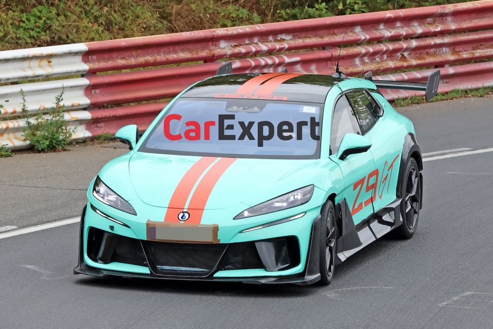 A mint green Denza Z9 GT with orange racing stripes on track at the Nurburgring, seen from the front