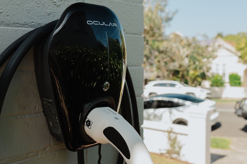 An Ocular brand wall-mounted home EV charger with a Type 2 charging connector, installed on the exterior wall of a residential property