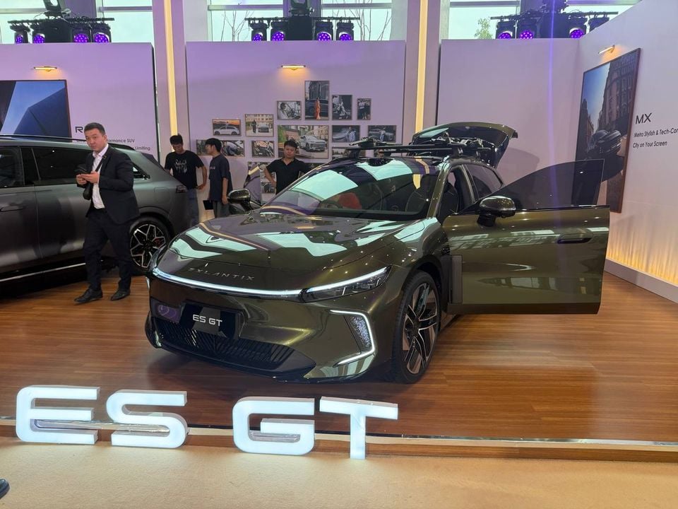Green Exlantix ES GT shooting brake shown from the front with a front door and tailgate open, behind an ES GT display sign.