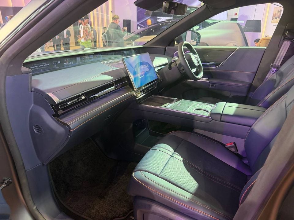 Exlantix right-hand-drive cabin viewed through the front passenger doorway, showing the steering wheel, wide dashboard display and central touchscreen.