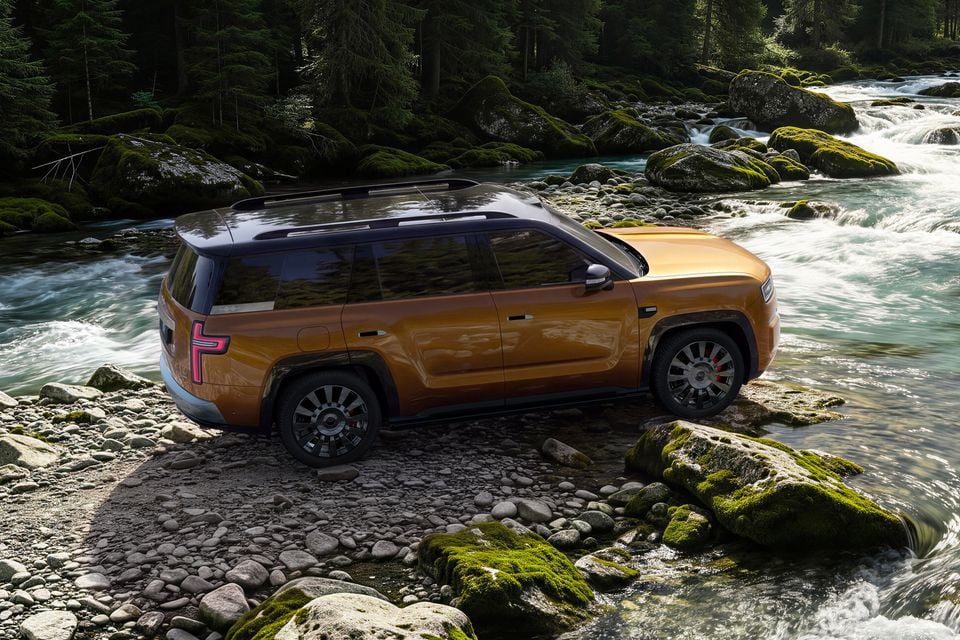 An orange Fangchengbao Tai 9 large SUV seen from the rear three-quarter angle, parked on rocky ground beside a flowing forest river