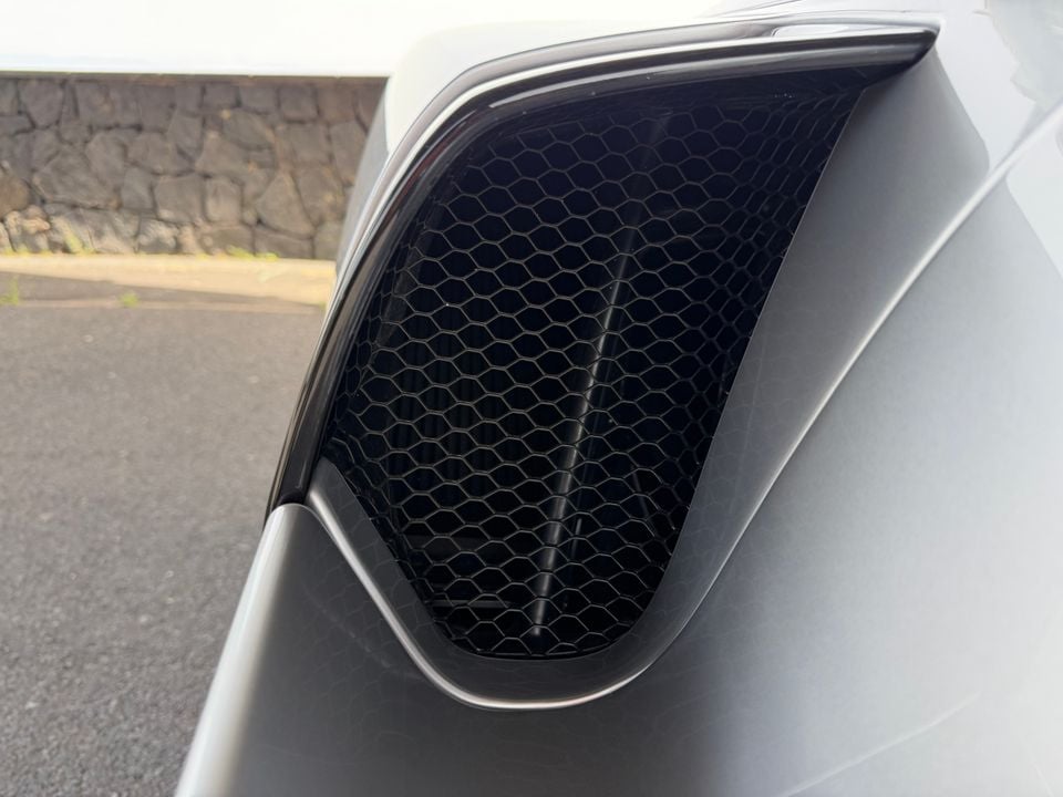 Close-up of a honeycomb mesh air intake vent on a white Ferrari's front bumper