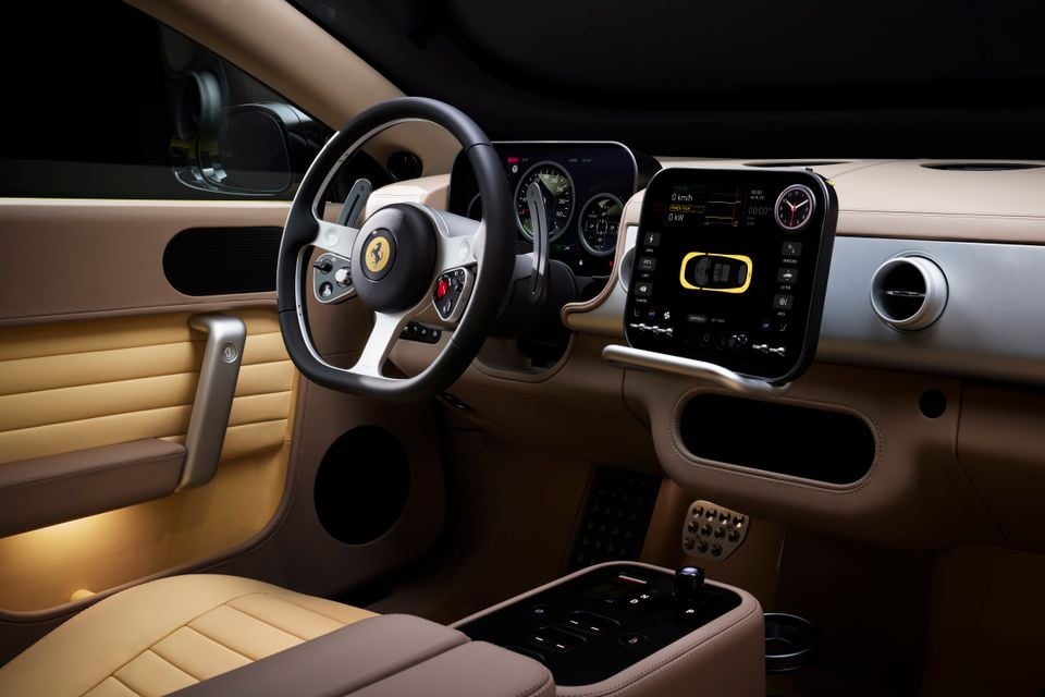 Ferrari Luce interior showing tan leather cabin, steering wheel with prancing horse badge, large central touchscreen infotainment display, and centre console