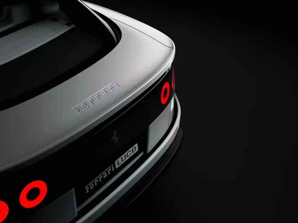 Close-up of the rear of a silver Ferrari Luce, showing circular tail lights and Ferrari badging against a dark studio background.