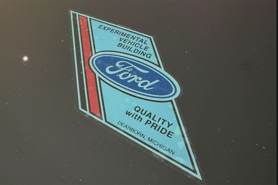 Ford Experimental Vehicle Building sticker reading 'Quality with Pride, Dearborn, Michigan' on the dark glass of a Ford Mustang ute