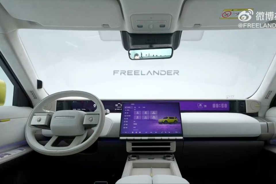 The interior dashboard of a Freelander SUV featuring a wide infotainment screen, digital instrument cluster, and white cabin trim