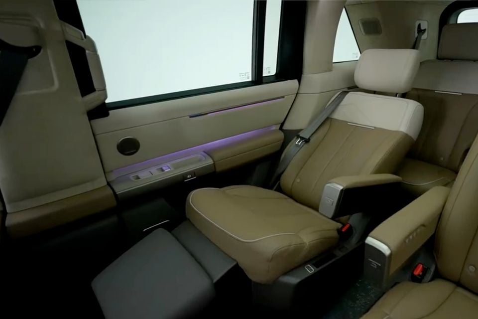 Beige leather rear passenger seat interior of a Land Rover Freelander with ambient purple lighting along the door panel and a footrest extended