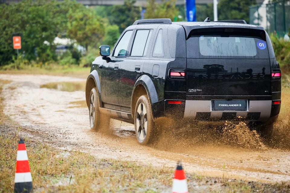 Dark Freelander 8 em uma esquina enlameada, visão traseira de três quartos.