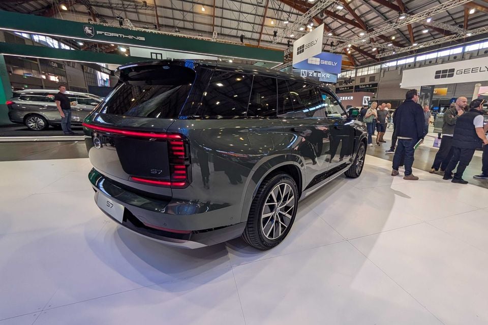 A dark grey GAC S7 SUV seen from the rear three-quarter angle on display at a motor show, with Geely and Zeekr brand signage visible in the background.