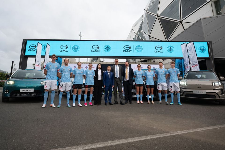 GAC Aion representatives and Melbourne City FC players pose in front of GAC Aion UT and Aion V electric vehicles at a sponsorship announcement event