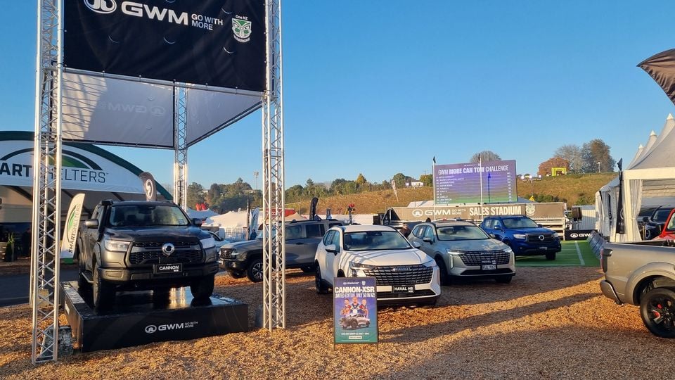 GWM display at a New Zealand outdoor event, featuring a GWM Cannon ute on a platform and several Haval and GWM vehicles including a white Haval H6 SUV, with branded signage and the GWM Sales Stadium in the background.