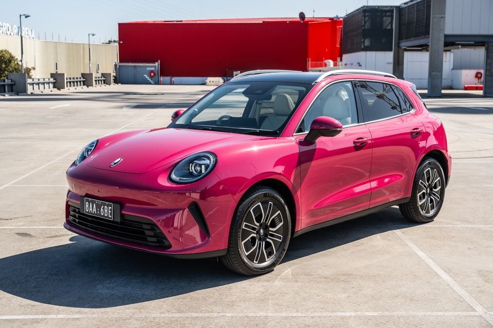 A pink GWM Ora 5 small electric SUV parked on an empty rooftop car park, seen from the front three-quarter angle