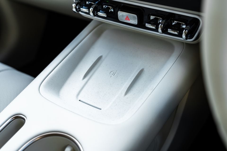 Wireless phone charging pad on the light grey centre console of a GWM Ora 5, below chrome toggle switches and a hazard light button