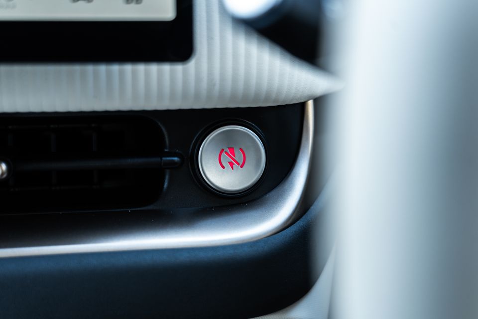 Close-up of the illuminated red-symbol button beside an air vent below the screen on the dashboard of a GWM Ora 5