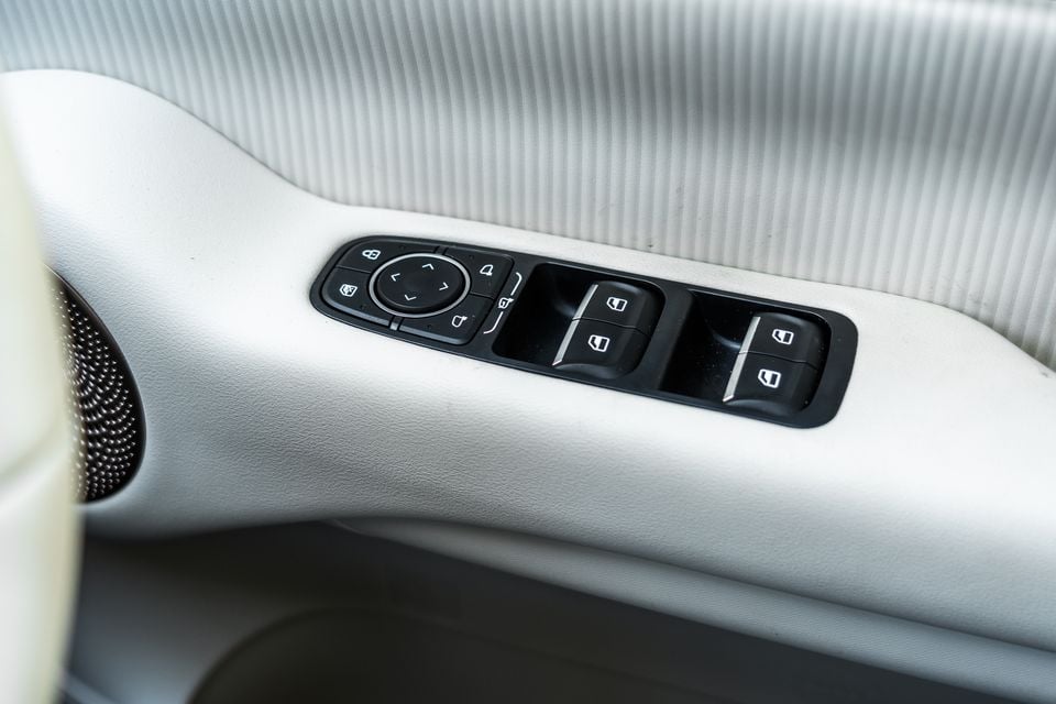 Window and mirror control switches on the light grey door trim of a GWM Ora 5, beside a door speaker grille