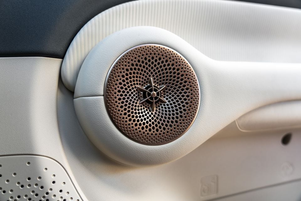 Close-up of a copper-toned speaker grille with a propeller-style centre on the cream door trim of a GWM Ora